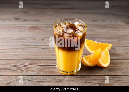 Leckeres erfrischendes Getränk mit Kaffee und Orangensaft auf einem Holztisch Stockfoto