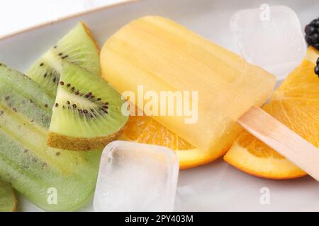 Köstliches Eis am Stiel, Eiswürfel und frisches Obst auf dem Teller, Nahaufnahme Stockfoto