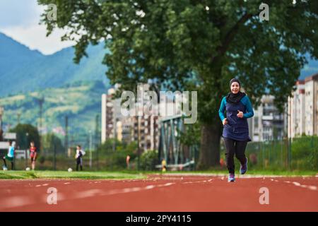 Eine muslimische Frau in einer Burka sportlich muslimische Kleidung, die auf einem Marathonkurs läuft und sich auf die nächsten Wettkämpfe vorbereitet Stockfoto