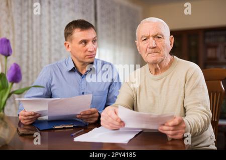 Mann, der seinem Vater beim Ausfüllen von Dokumenten hilft Stockfoto