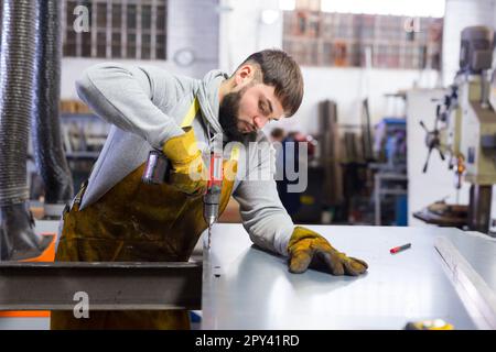 Arbeiter bohren Metallteile mit Handbohrer Stockfoto