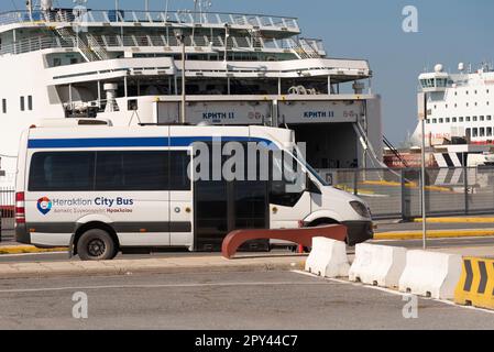 Heraklion, Kreta, Griechenland, EU. 2023. Ein Stadtbus von Heraklion, der im Hafen auf Passagiere wartet, mit einer Fährenlandschaft. Stockfoto