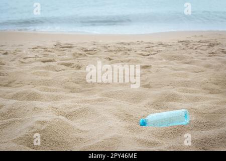 Plastikflasche am Strand nahe dem Meer, Platz für Text. Recycling-Problem Stockfoto
