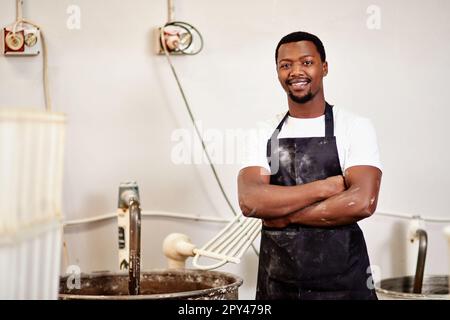 Meine Bäckerei ist einen Versuch wert. Ein selbstbewusster junger Mann, der in einer Bäckerei arbeitet. Stockfoto