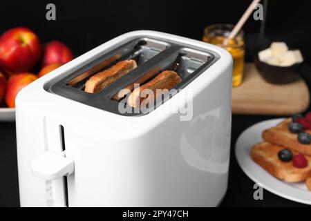 Moderner Toaster mit Brotscheiben auf dem Tisch, Nahaufnahme Stockfoto