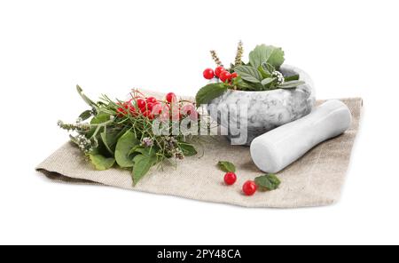Stoff- und Marmormörtel mit verschiedenen Kräutern, Beeren und Stößel auf weißem Hintergrund Stockfoto