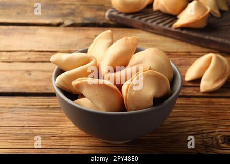 Leckere Glückskekse mit Voraussagen auf Holztisch, Nahaufnahme Stockfoto