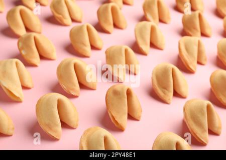 Viele leckere Glückskekse mit Vorhersagen auf pinkfarbenem Hintergrund Stockfoto