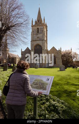 Eine Frau, die eine Informationstafel vor der St.-Lorenz-Kirche Evesham liest. Die Kirche, jetzt überflüssig, steht neben der Allerheiligen Kirche. Stockfoto