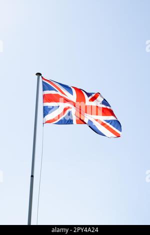 Eine Unionsflagge, auch bekannt als Union Jack, die im Wind gegen einen blauen Himmel bläst. Stockfoto