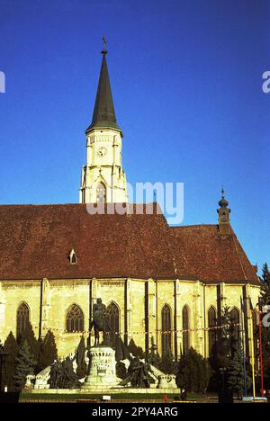 Cluj-Napoca, Rumänien, ca. 1999. Außenansicht von St. Michaels Kirche, ein historisches Denkmal aus dem 14. Jahrhundert, mit der Statue von Matthias Corvinus davor. Stockfoto