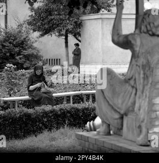 Mures County, Sozialistische Republik Rumänien, ca. 1976. Alte Frau strickt auf einer Bank in der Stadt. Stockfoto