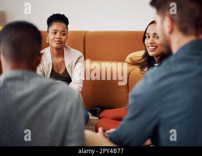 Während einer Pause aufholen. Eine vielfältige Gruppe von Geschäftsleuten, die tagsüber im Büro zusammensitzen und ein Meeting abhalten. Stockfoto