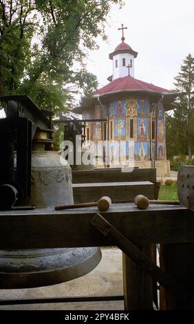 Timis County, Rumänien, ca. 2002. Außenansicht des christlich-orthodoxen Klosters Izvorul lui Miron (geboren 1929). Große Glocke und Holzhämmer. Stockfoto