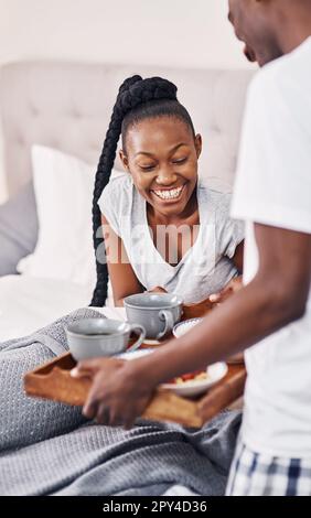 Niemand brachte mir je Frühstück im Bett. Ein junger Mann bringt seiner Freundin Frühstück ins Bett. Stockfoto