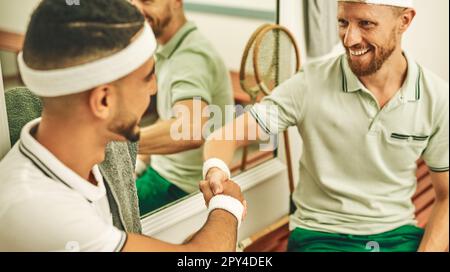 Die soziale Seite des Sports. Zwei junge Männer, die sich nach einem Squash-Spiel in der Umkleide die Hand schütteln. Stockfoto