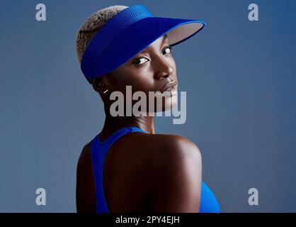 Hör nie auf, an einem besseren Ich zu arbeiten. Studioaufnahme einer sportlichen jungen Frau, die ein Visier trägt, während sie vor blauem Hintergrund posiert. Stockfoto