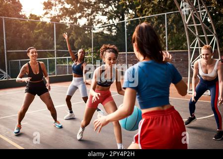 Sie hat es fast geschafft. Eine vielfältige Gruppe von Sportlerinnen, die tagsüber gemeinsam ein Wettkampfspiel mit Basketball spielen. Stockfoto
