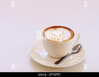 Kaffeetasse, Cappuccino und Herz in Schaum im Studio isoliert mit weißem Hintergrund. Café-Drink, Liebe zum Schreiben und schaumige Getränke Kunst mit Milch und Stockfoto