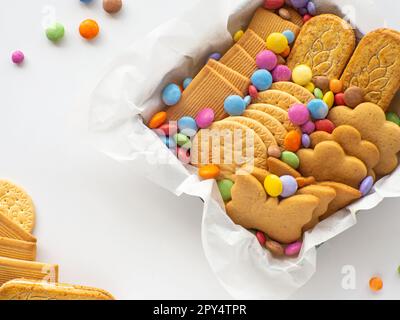 Verschiedene Kekse und Süßigkeiten im Korb. Muttertagskonzept. Handmade Care Paket, saisonale Geschenkbox mit Süßigkeiten, Dragee und Keksen für die Familie, Stockfoto