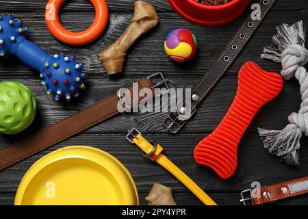 Flach liegend mit Hundehalsband, Spielzeug und Schüssel auf schwarzem Holztisch Stockfoto