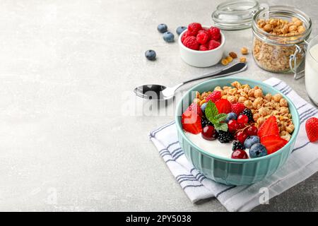 Schüssel mit leckerem Müsli und Beeren auf einem hellgrauen Tisch. Platz für Text Stockfoto