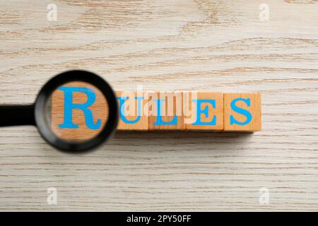 Lupe über Wort Regeln aus Würfeln mit Buchstaben auf Holztisch, Draufsicht Stockfoto