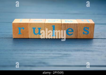 Wortregeln aus Würfeln mit Buchstaben auf hellblauem Holztisch Stockfoto