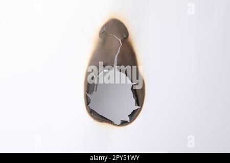 Verbranntes Loch im Papier auf weißem Hintergrund Stockfoto