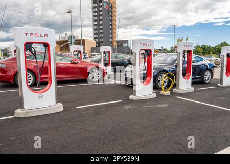 Halmstad, Schweden - Juli 10 2022: Lange Reihe von Tesla-Autos laden beim Tesla Supercharger Halmstad Stockfoto