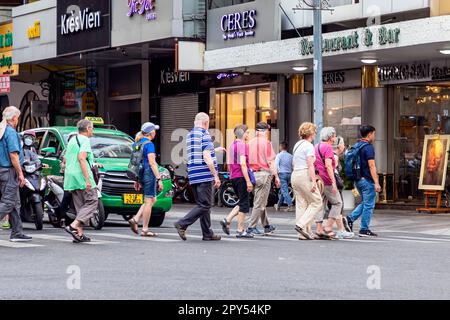 Amerikanische Reisegruppe überquert die Straße im Zentrum von Ho-Chi-Minh-Stadt, Vietnam Stockfoto