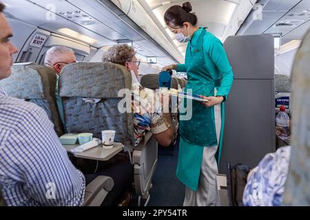 Vietnam Airlines Kabinenpersonal kümmert sich um die Passagiere, trägt AO dai Uniform auf dem Flug von Bangkok nach Vietnam Stockfoto