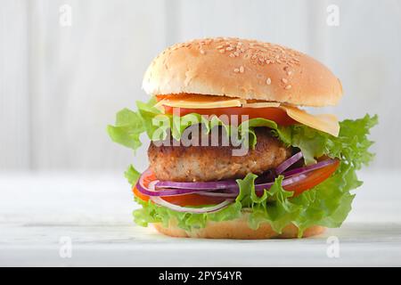 Fleischburger mit Tomaten, Käse, Zwiebeln auf dem Tisch Stockfoto