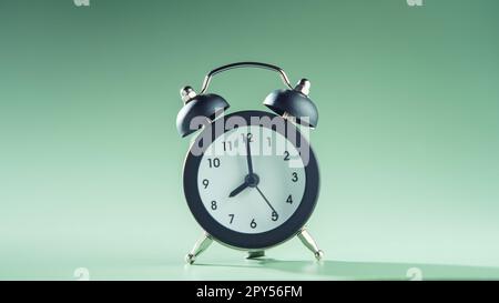 Blaue Uhr zeigt acht Uhr auf grünem Hintergrund. Zeit, Zeitplan, Countdown, Wecker, Zeitplan, Abgabetermin. Stockfoto