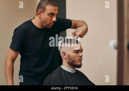 Der Friseur frisiert im Friseursalon mit einer Schere Stockfoto