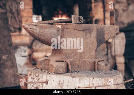 Bearbeiten Sie Metall mit einem Hammer auf Amboss in Schmiede. Schlagen Sie das Eisen im Freien in der Werkstatt mit Feuer an. Metallarbeiten, Schmieden. Stockfoto