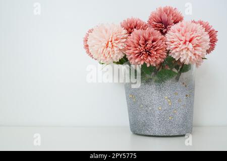 Strauß aus rosafarbenen künstlichen Frottblumen in einer grauen silbernen Vase auf weißem Hintergrund. Stillleben, Dekoration möglich. Zimmereinrichtung. Geben Sie Platz für Text frei. Stockfoto