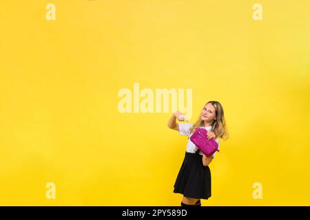 Glückliches Schulmädchen mit farbigen Bleistiften und einem Federmäppchen in der Hand Stockfoto