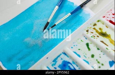 Palette von Aquarellfarben, Pinsel und Aquarellpapier, Nahaufnahme. Stockfoto