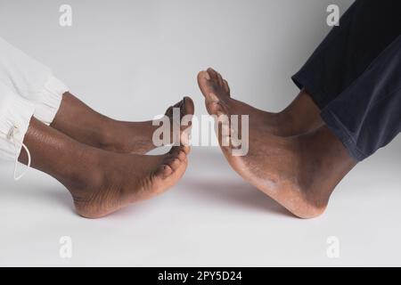 Nahaufnahme afroamerikanischer Mann und Frau Beine, die sich berühren, isoliert auf weißem Hintergrund halten für Liebe und Heilkonzept Stockfoto