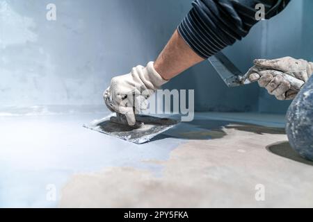 Verteilen der Isolierung auf dem Beton mit einer Kelle Stockfoto