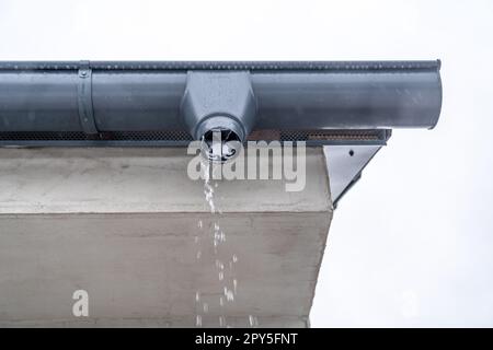 Dachrinne mit fließendem Regenwasser auf dem Dach des Gebäudes Stockfoto