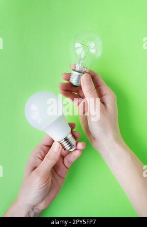 Ein Set aus zwei Arten von Lampen, LED und Glühlampe, in den Händen eines Mädchens isoliert auf grünem Hintergrund. Energiesparlampen. Stockfoto