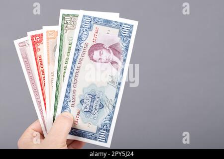 Altes chilenisches Geld in der Hand auf grauem Hintergrund. Stockfoto