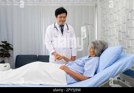 Seniorin und Ärztin. Asiatischer Arzt mit Stethoskop, um die Pulpen des älteren Patienten zu prüfen. Stockfoto