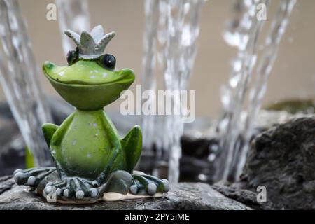 Eine Figur des Froschprinzen sitzt am Rand eines Brunnens. Stockfoto