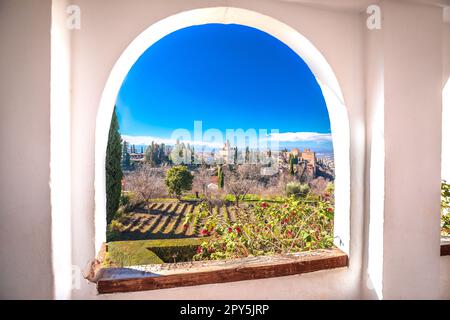 Blick auf die antike Alhambra durch ein Steinfenster, UNESCO-Weltkulturerbe in Granada, Andalusien in Spanien Stockfoto