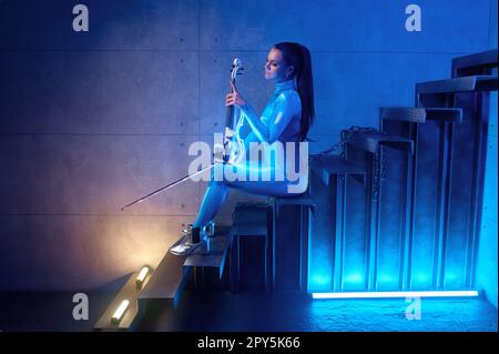 Futuristisches Konzert einer jungen Violinistin im Neonlicht Stockfoto