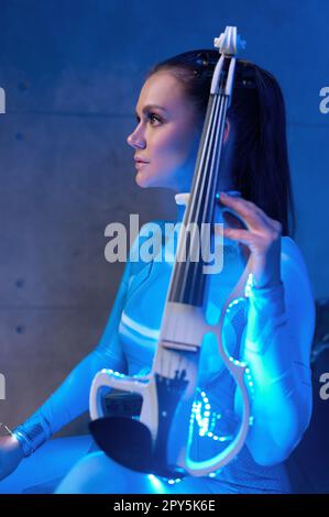 Seitenansicht einer jungen Violinistin mit elektrischer Geige Stockfoto