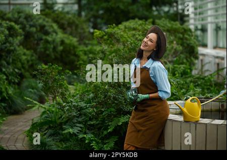 Positiv lächelnde Gärtnerin mit Blumentöpfen im handselektiven Fokus Stockfoto